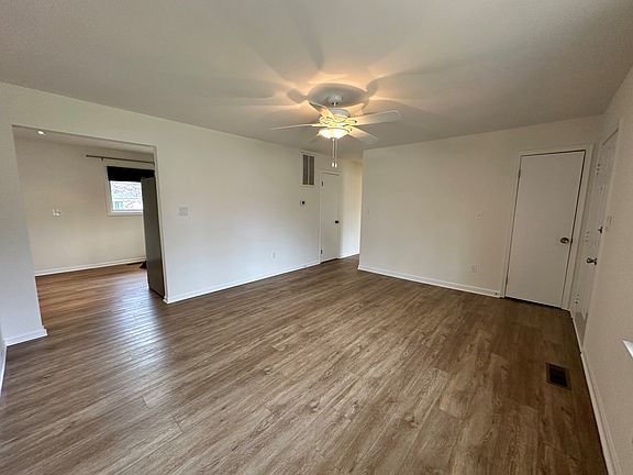 Another view of the living room and coat closet (the door on the right). The opening on the left leads to the kitchen and the hallway leads to three bedrooms, bathroom, laundry, a large utility room and pantry.