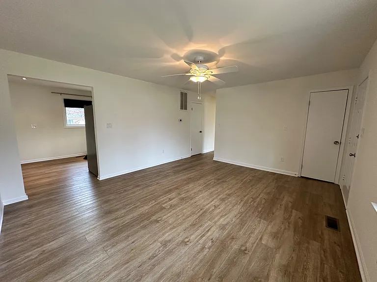 Another view of the living room and coat closet (the door on the right). The opening on the left leads to the kitchen and the hallway leads to three bedrooms, bathroom, laundry, a large utility room and pantry.