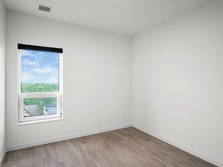 Bright, airy room with large window overlooking lush greenery and light wood flooring. Bright, airy room with large window overlooking lush greenery and light wood flooring.