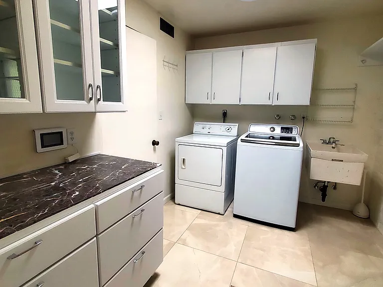 Laundry room with utility sink and cabinets, and entry from garage.