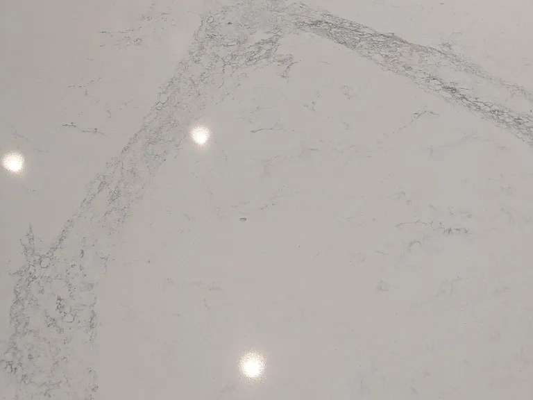 Detailed close up of kitchen quartz counters. Creamy white with gray veining.