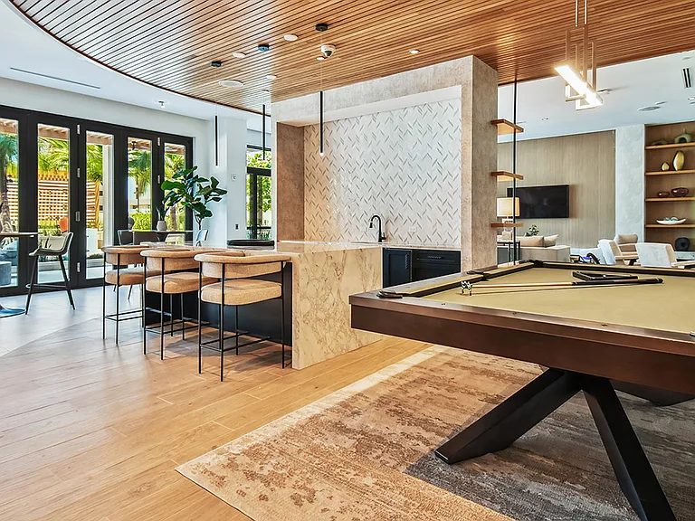 Griffis West Palm apartments resident lounge with pool table, bar with stools, and dining tables.