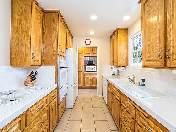 Clean galley kitchen with fine cabinets, white til