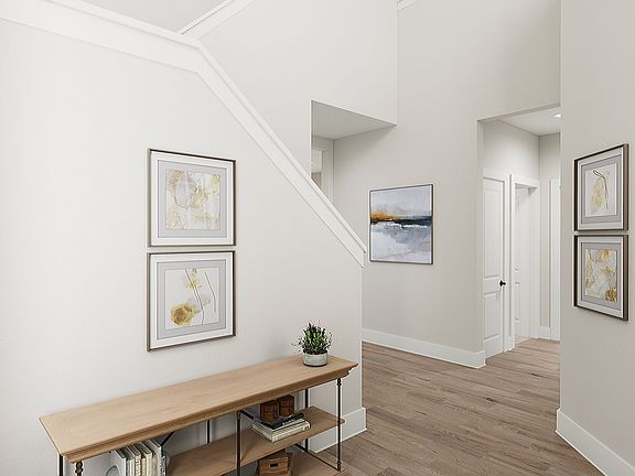 A bright and airy hallway with framed artwork on the walls, a wooden bench, and a potted plant, lead