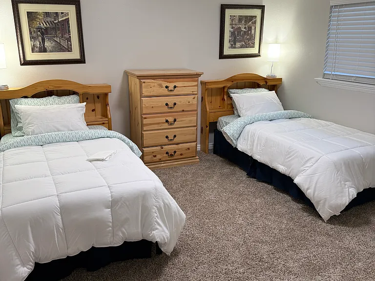 Second bedroom with two twin beds, dresser, and nightstands with storage. Twin lamps with two charging ports.