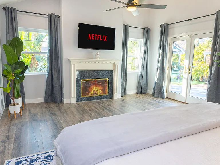 Cozy up in the master bedroom featuring a warm fireplace, mounted TV, and stunning views of the mountains and pool. The perfect blend of comfort and style for a relaxing stay.