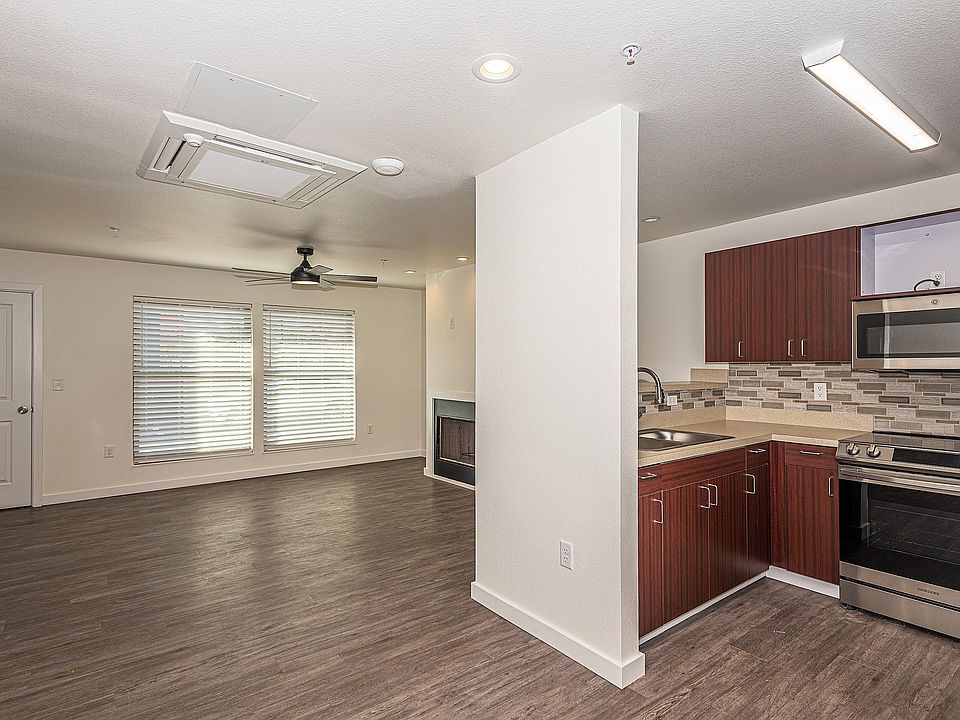 Kitchen with stainless sink, decorative backsplash, ceiling fan, luxury vinyl wood-style floors, and stainless steel appliances