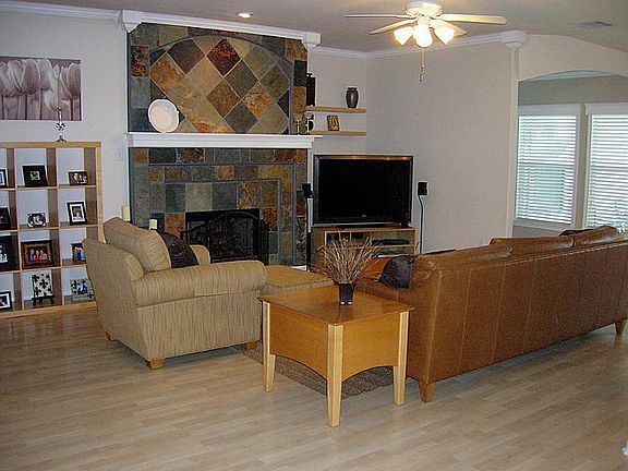 Open & airy family room has custom slate fireplace surround, birch-like laminate floor,crown molding, wall of windows oversees the covered patio and pool.
