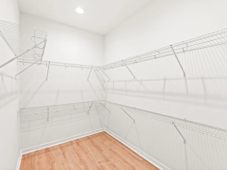 Walk-in closet with wraparound wire shelving and hanging space, offering ample storage and easy organization.