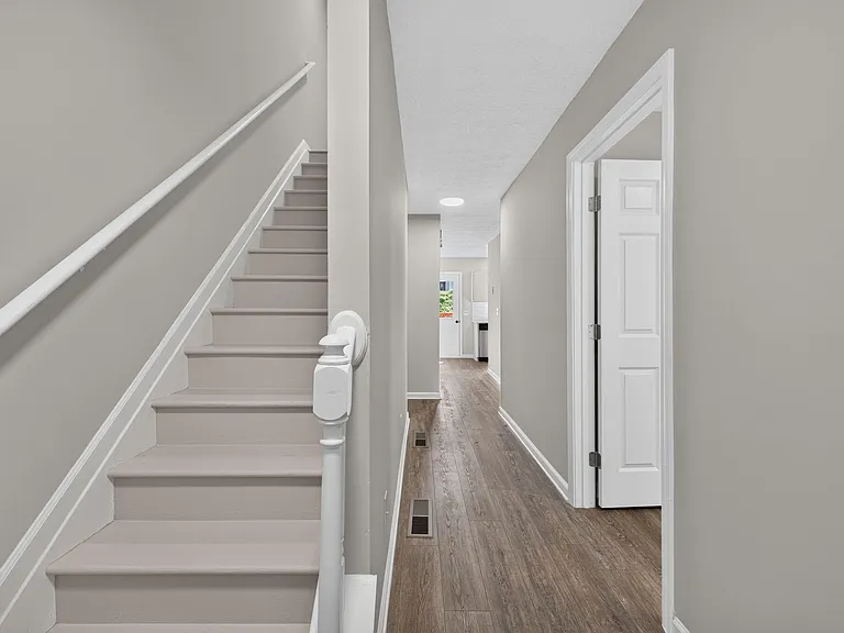 Wide entry hallway with stair access, durable wood-look flooring, and clean lines connecting to the main living areas.
