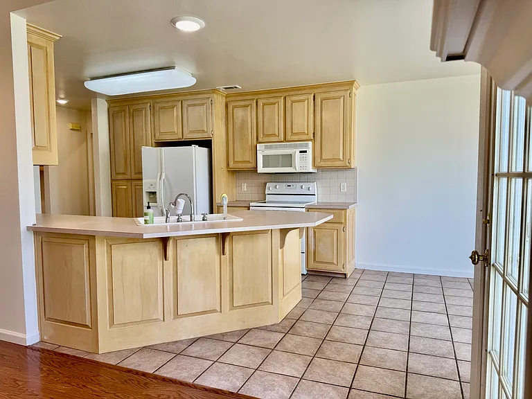 Open kitchen with peninsula breakfast bar, custom cabinetry, tile backsplash, and tile floors