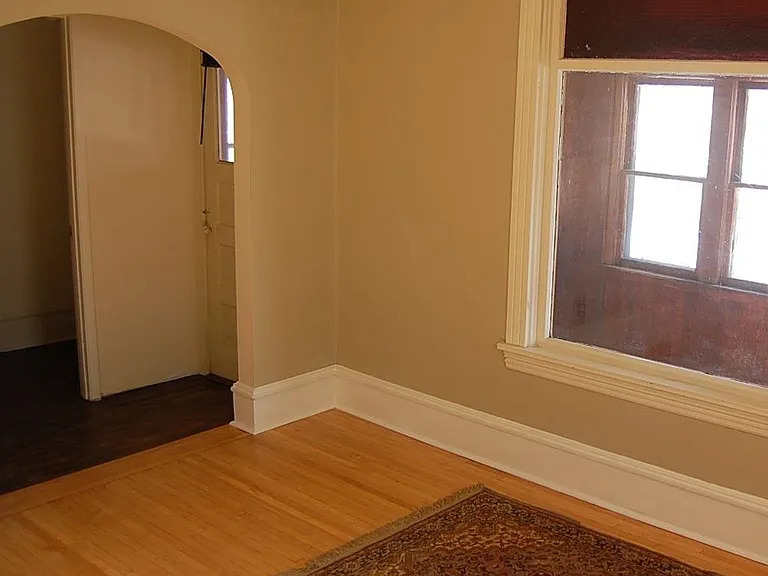 Large front bedroom has a picture window looking out to an enclosed porch