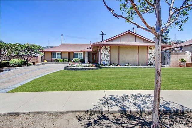 Front of the home with beautiful driveway and flower beds.