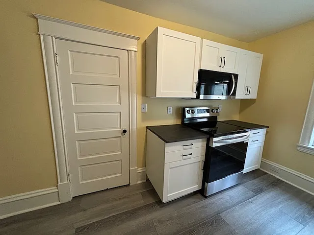 Kitchen, cupboards, microwave, and electric stove.
