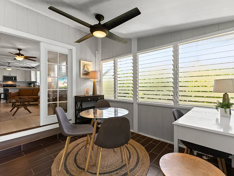 Enclosed lanai adds additional living space, a futon sofa, chair, TV, small dining set for 3-4, and a desk. Two large fans and lots of windows keep this area cool.