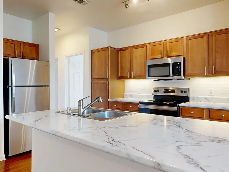Apartment Kitchen with Stainless Steel Appliances, Quartz counter tops and Wood Style Flooring.