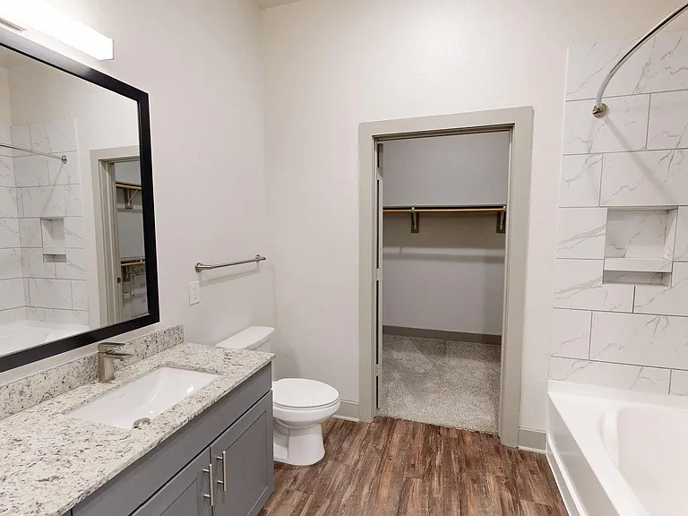 Apartment Bathroom with Wood Style Flooring and Spacious Closet.