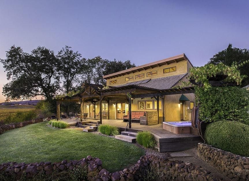 Expansive pergola covered porch has some built in seating and a dining table.