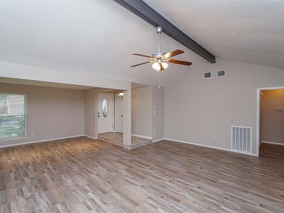 Spacious open living area with soaring ceiling Gray plank laminate flooring, ceiling fans throughout.