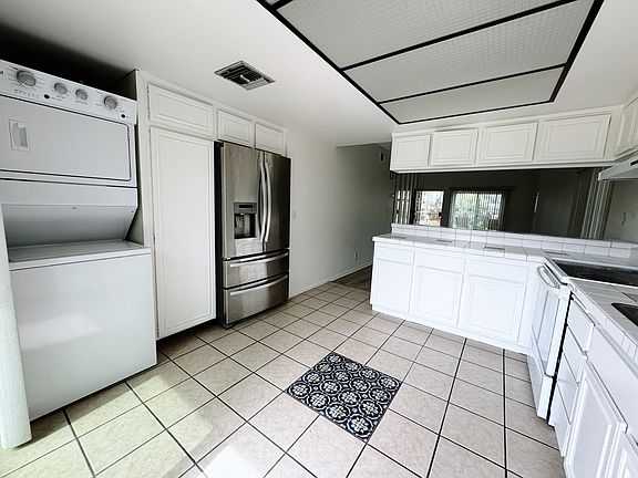 The kitchen with white cabinets and stainless steel appliances. You will find a stackable washer and dryer for your convenience.