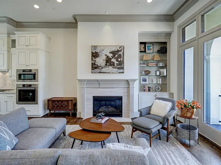 A sun-filled open concept living space includes custom built-ins, gas log fireplace, and balcony access.
