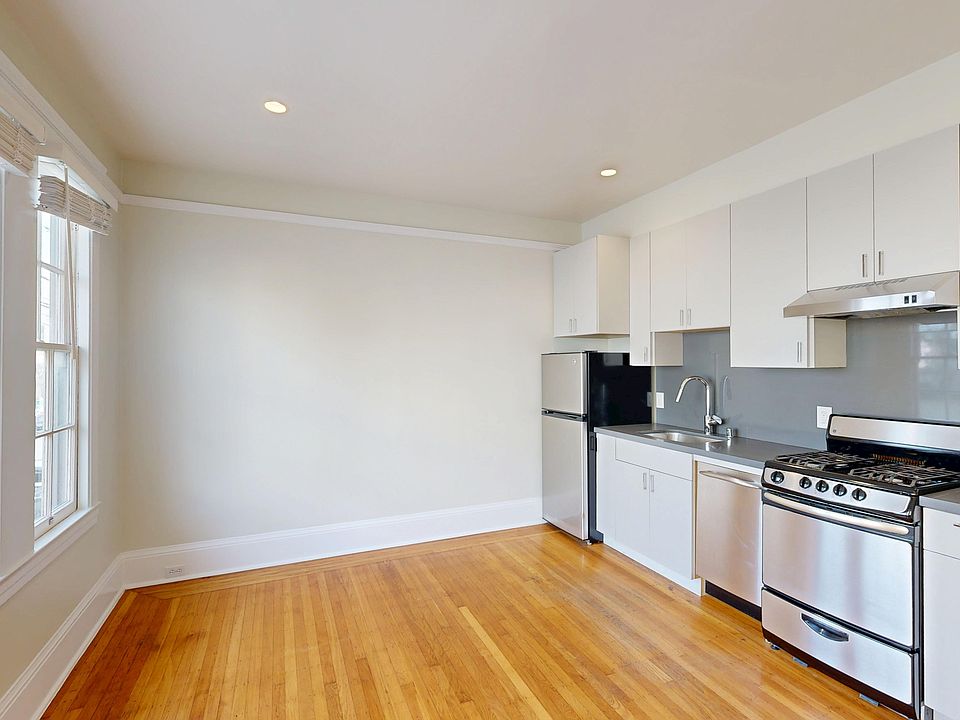Kitchen with cabinetry, wood flooring, stainless appliances, and large window