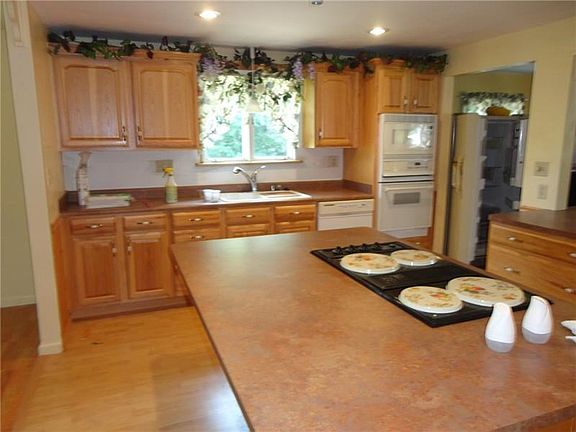 LARGE EAIN KITCHEN WITH OAK CABINETRY, DOUBLE OVENS AND CENTER ISLAND WITH ELECTRIC COOK TOP. SEATING FOR 6+ AROUND THE ISLAND.