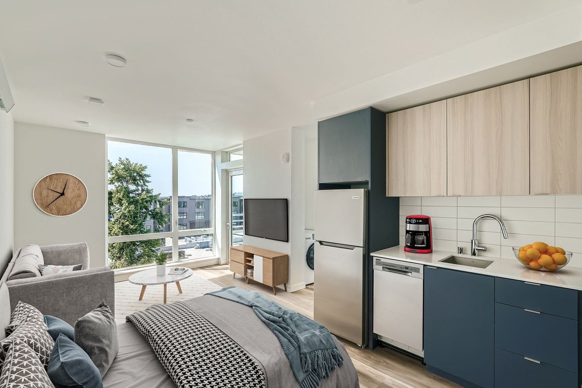 Enjoy the comfort and style of this spacious bedroom at Anker Ballard, complete with a cozy bed, functional desk, and large windows that fill the room with natural light.
