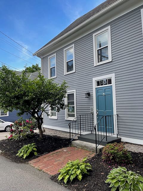 View of the front of the Colonial Styled house that enters into a common area with inside mailboxes and stairs leading to the second/third floor Unit