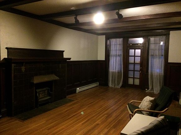 Livingroom without furniture. You can see the wainscoting, 10 panel glass door with side lights to front porch, all original fireplace with mantel, hood and wood grate. Original hardwood floors throughout.