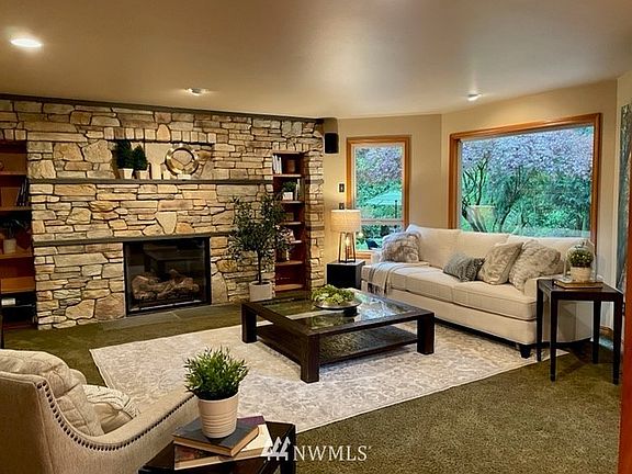 The living room is beautifully accented with a lodge-worthy custom fireplace. Large picture windows overlook the patio, back yard and trees beyond. 