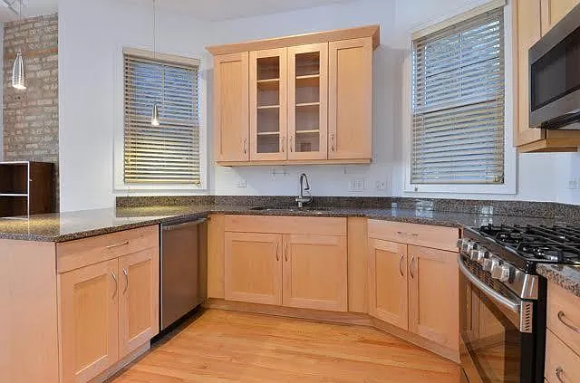 KITCHEN with granite counters, ample wood cabinets, breakfast bar, ss appliances, pendant lighting and natural light