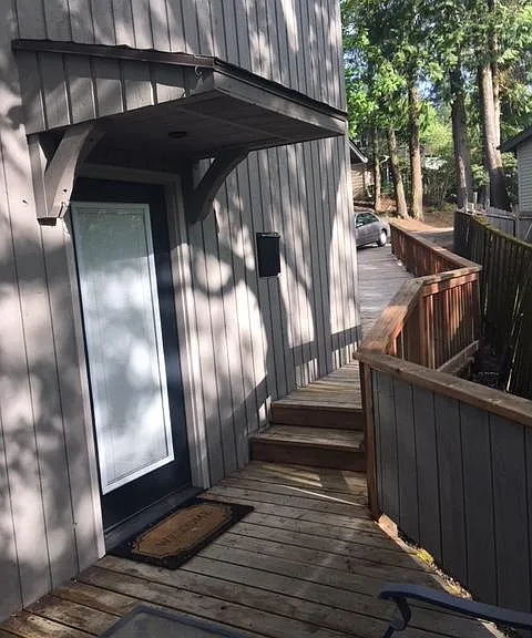 This is the private entrance (looking from deck back up to the driveway). Your approach offers privacy and is mostly secluded from the main house. Walkway has stair lighting. 

(Note: home repainted white recently)