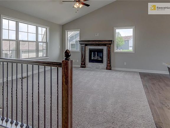 Custom tiled gas fireplace with stained mantel, large windows and ceiling fan in great room. Square metal stair spindles in choice of black or oil rubbed bronze.