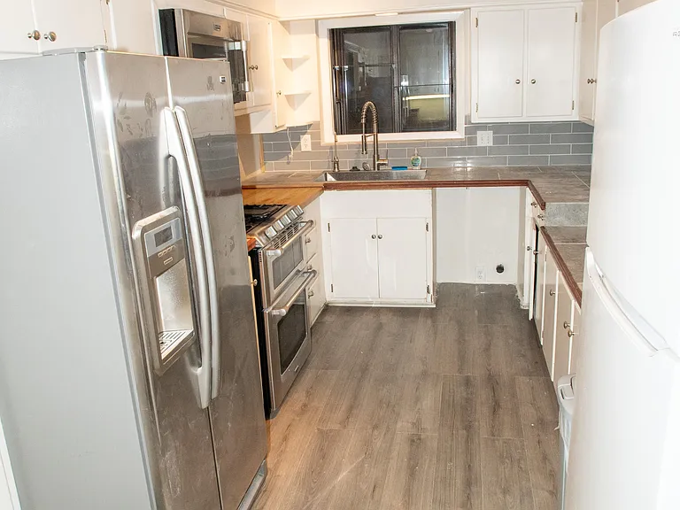 Full kitchen features plenty of cabinet space with a microwave, stove, oven, and two refrigerators.
