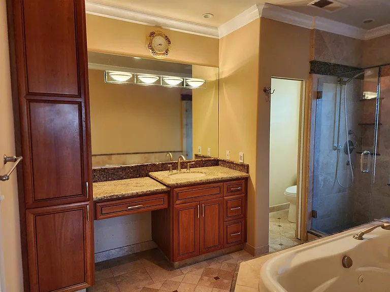 Primary bathroom with beautiful custom tile, cabinets, vanity, jacuzzi tub, large walk in shower and separate private toilet closet.