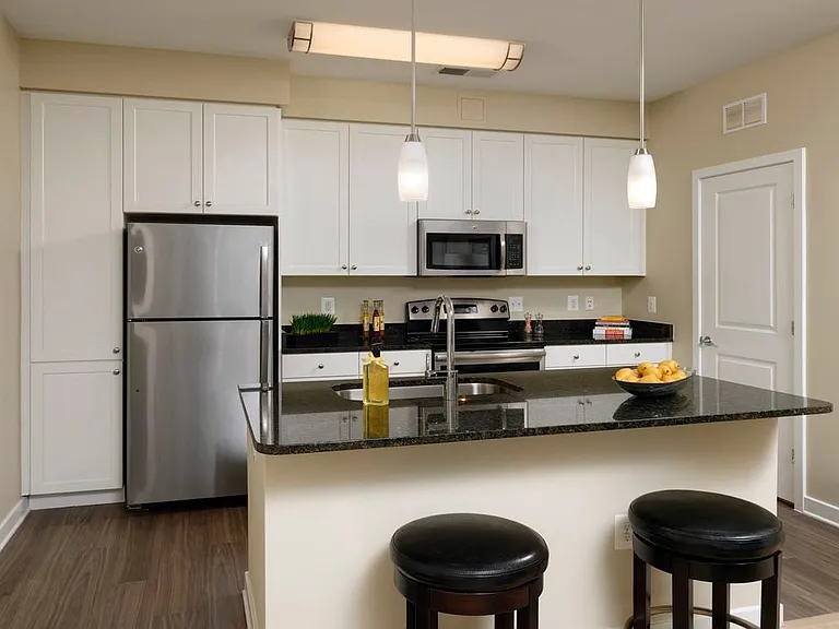 Open concept kitchen with white shaker cabinetry, granite countertops, kitchen island, stainless steel appliances and hard surface flooring