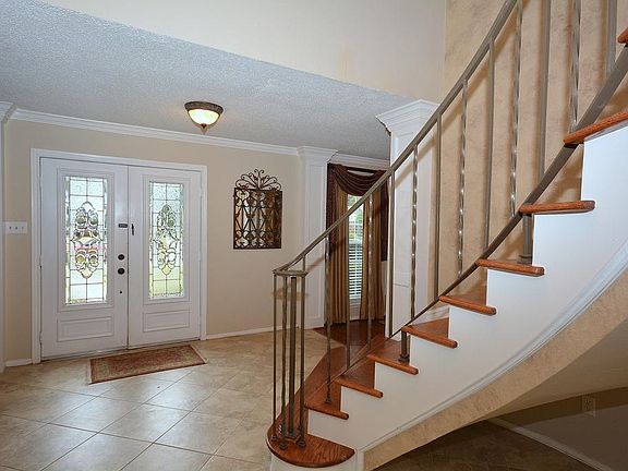 Open entry with high ceilings, recent tile, iron railing on staircase