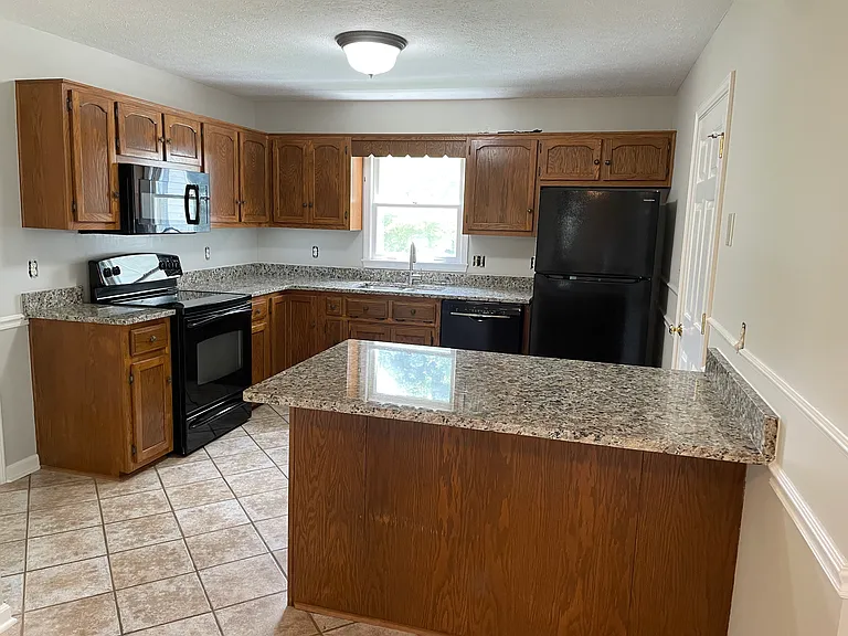 Brand new granite countertops and refrigerator in kitchen.