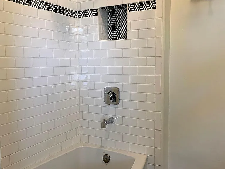 View of the bathroom with new shower/tub, tile and fresh paint.