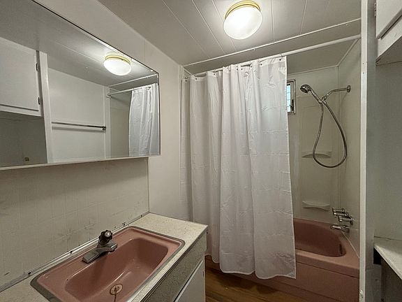 Bathroom with tub/shower, sink with 2'x3' mirror.