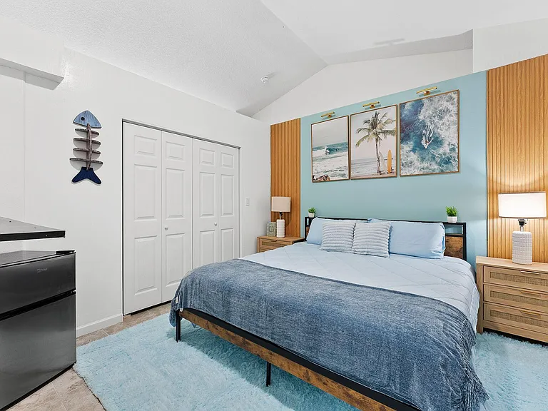 Well-appointed bedroom with a full bed, nightstands, and a large closet, plus an in-room mini fridge and counter space.