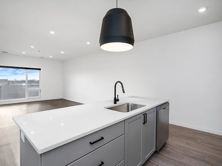 Modern kitchen with sleek island and large windows offering natural light, featuring stylish cabinetry and contemporary lighting. Modern kitchen with sleek island and large windows offering natural light, featuring stylish cabinetry and contemporary light