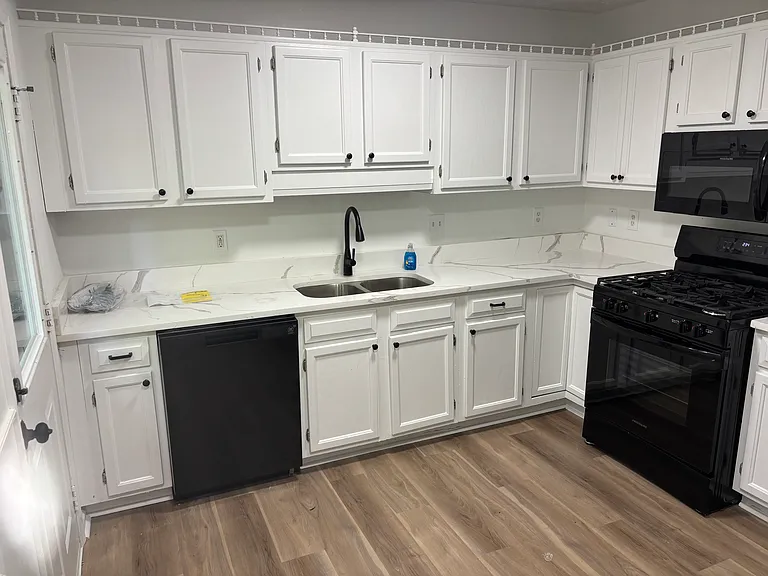 Kitchen with white quartz countertops and new black appliances