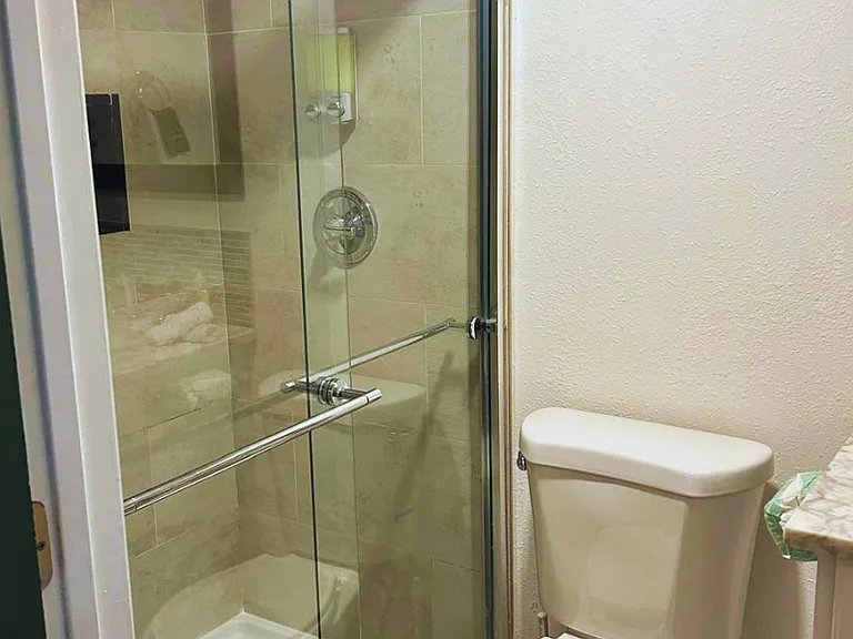 Immaculate bathroom with shower, toilet, mirror, towels, and well-kept towel racks.