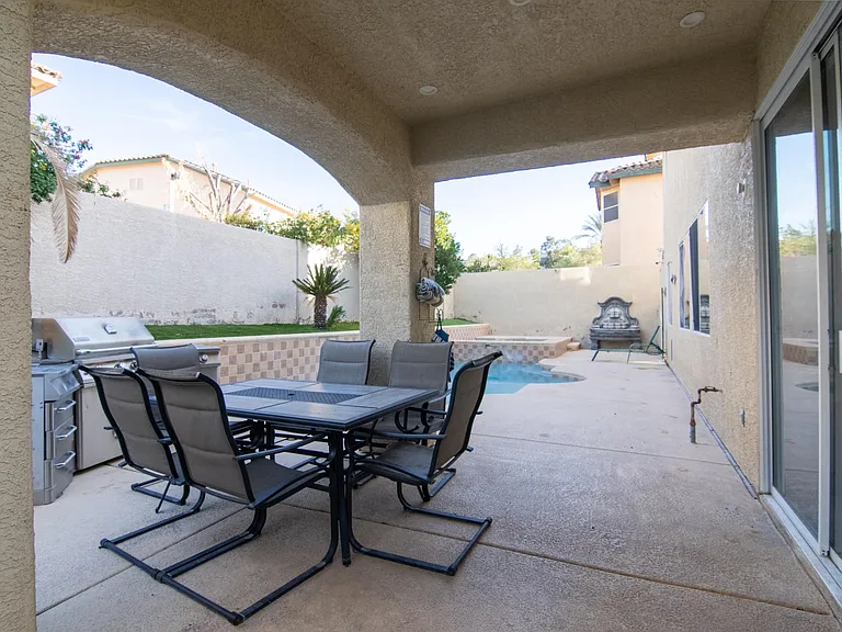 Covered backyard patio with outdoor dining, built-in grill, and a small poolideal for relaxing or entertaining.