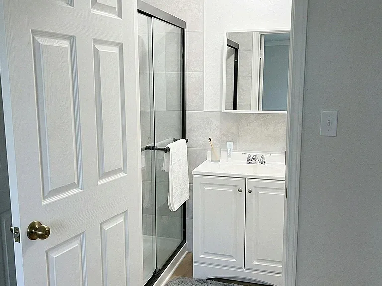 Well-appointed bathroom with a glass-enclosed shower, tiled surround, and vanity with mirror and storage below.