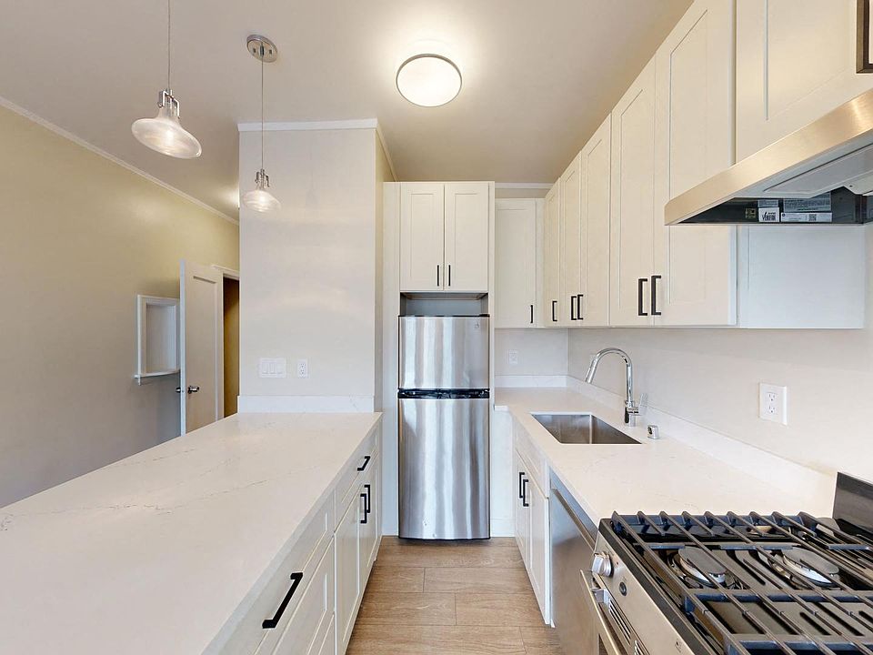 Kitchen with multiple cabinets, refrigerator, stove, range hood, and sink