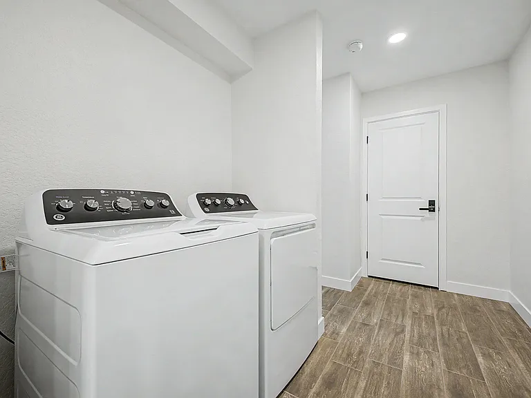 Dedicated laundry room with full-size washer and dryer, durable tile flooring, and convenient interior access door.