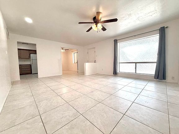Spacious living room, ceiling fan, lights, window.